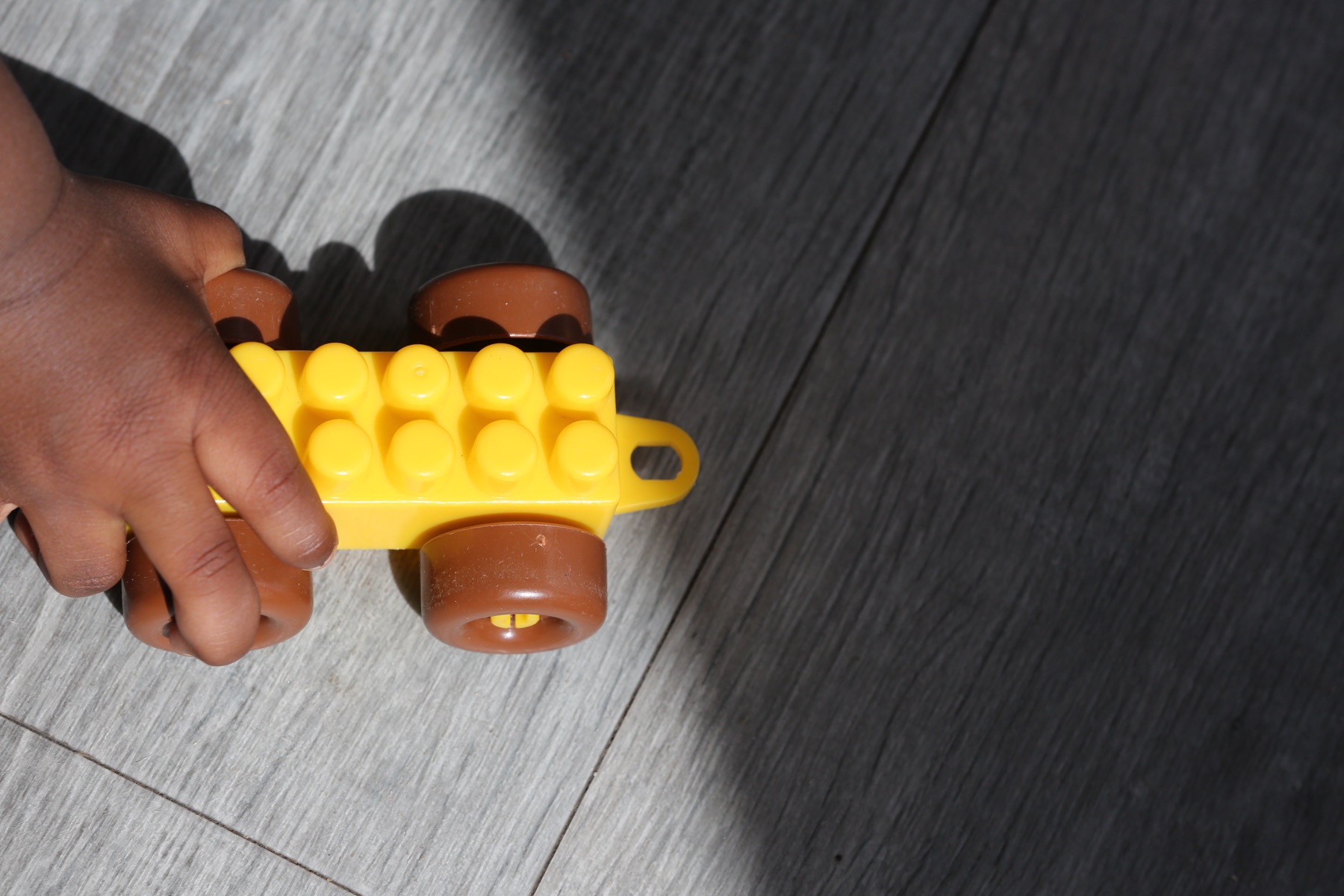 A child's hands holding a yellow toy brick